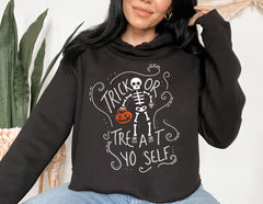 Black crop hoodie with a skeleton holding a pumpkin that says trick or treat yo self - HighCiti