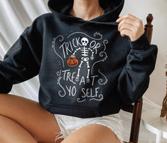 Black hoodie with a skeleton holding a pumpkin that says trick or treat yo self - HighCiti