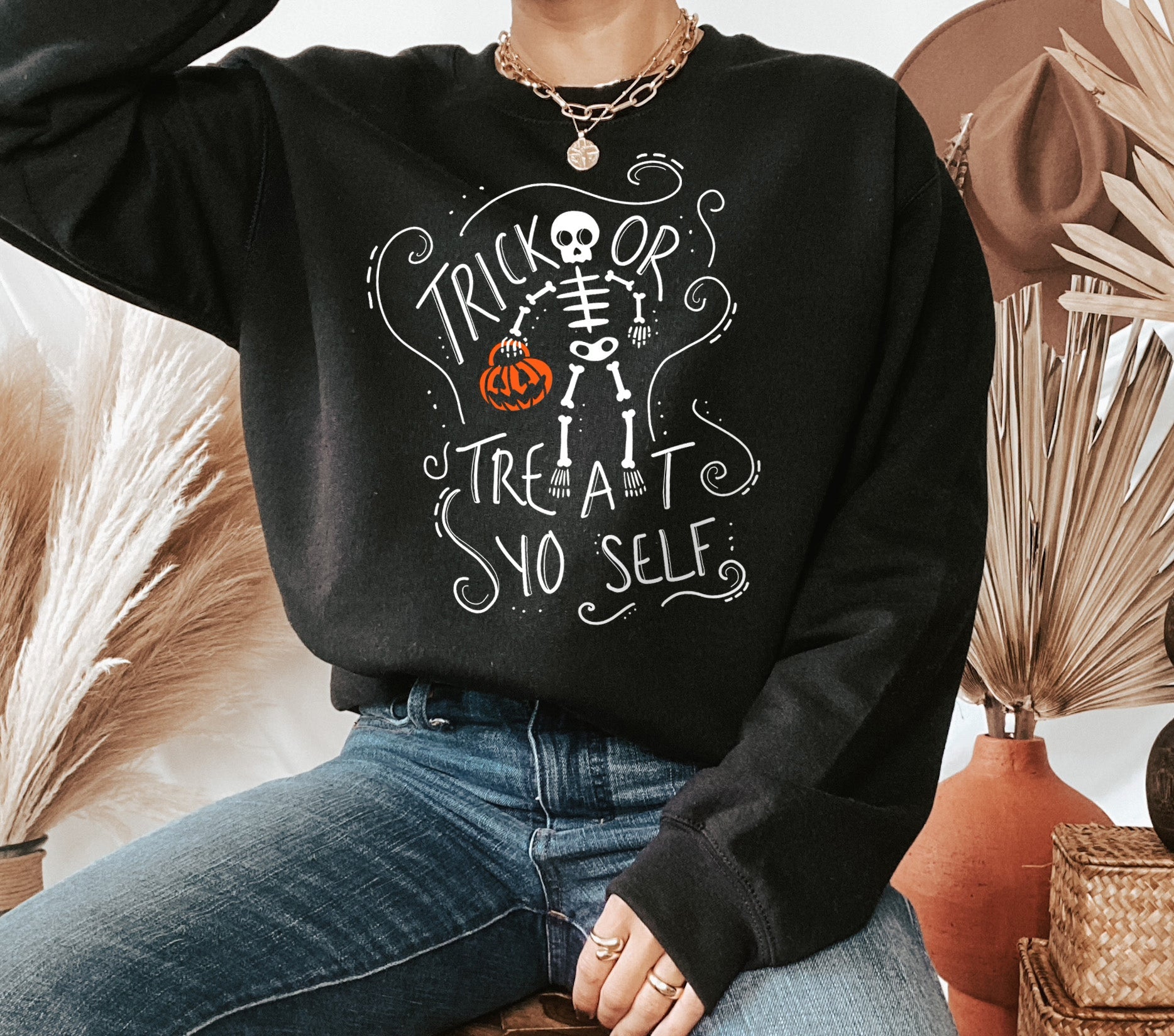 Black sweater with a skeleton holding a pumpkin that says trick or treat yo self - HighCiti