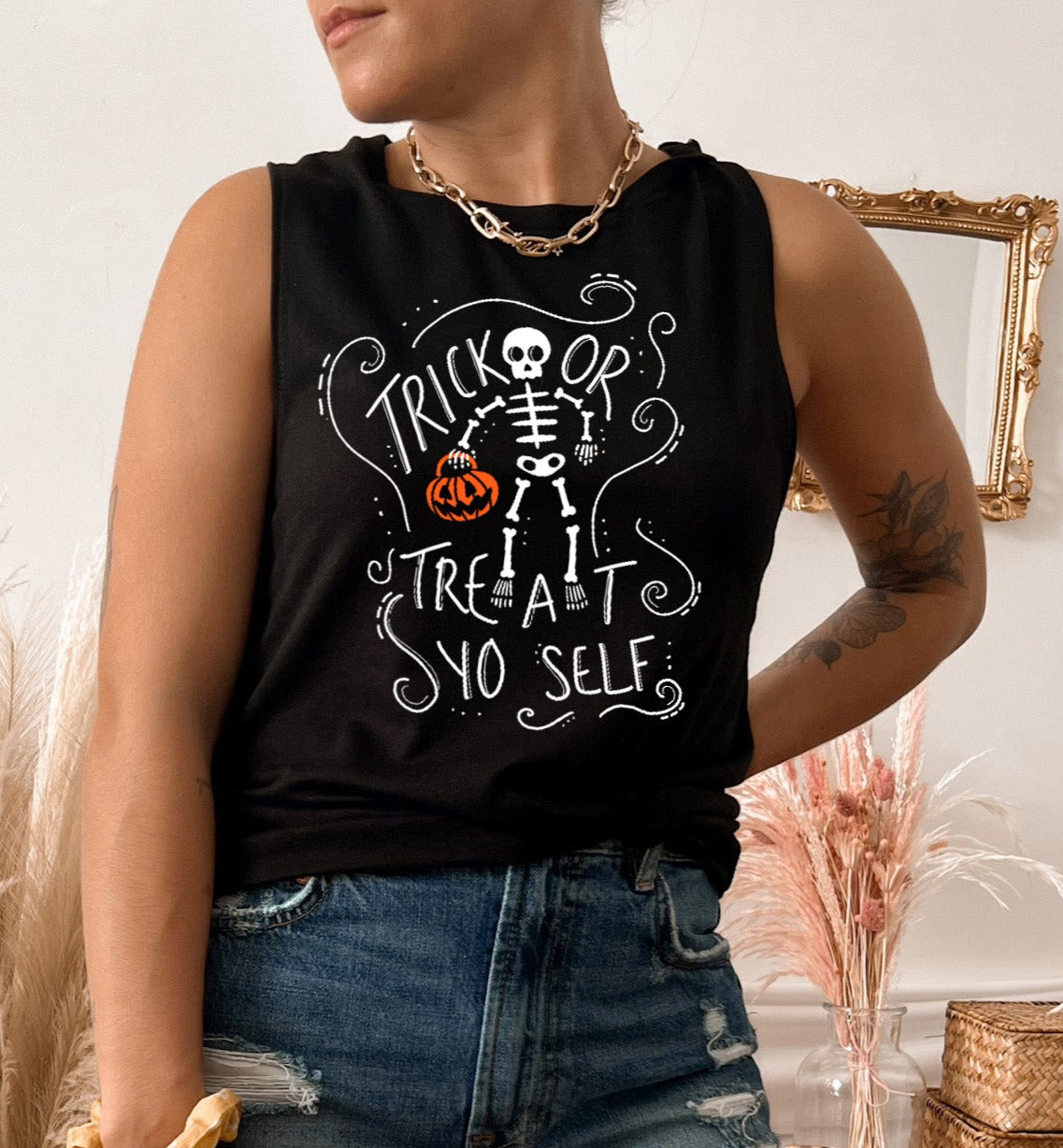 Black muscle tank with a skeleton holding a pumpkin that says trick or treat yo self - HighCiti